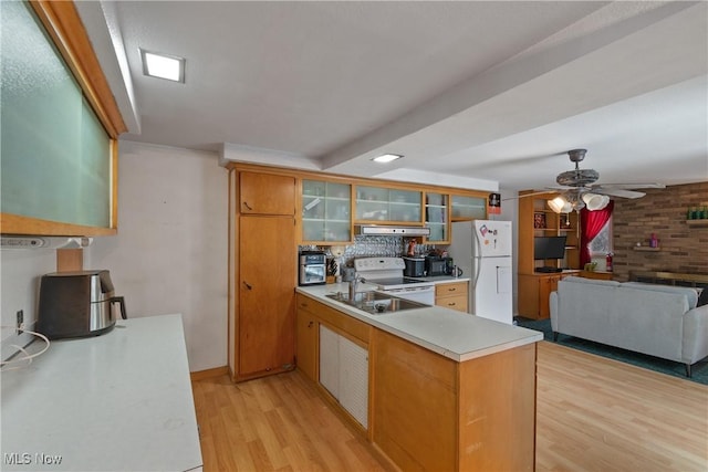 kitchen featuring white appliances, glass insert cabinets, open floor plan, light countertops, and under cabinet range hood