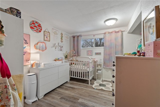 bedroom with a crib and light wood finished floors