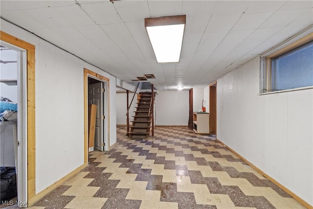 finished basement featuring stairs, wood walls, baseboards, and tile patterned floors