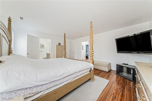 bedroom with a textured ceiling and dark hardwood / wood-style flooring