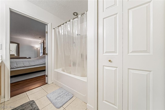 bathroom with tile patterned flooring, shower / bath combo, and a textured ceiling