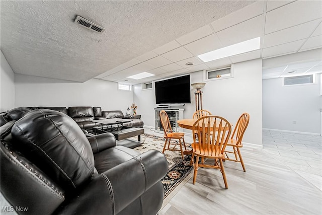 living room featuring a drop ceiling, a textured ceiling, and light hardwood / wood-style flooring