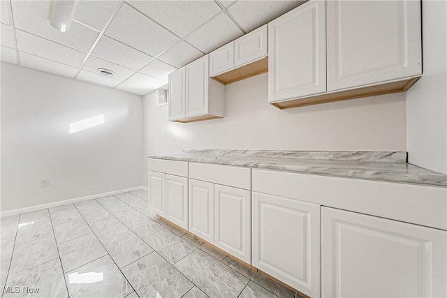 kitchen with a drop ceiling and white cabinets