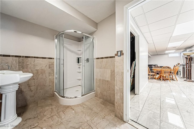 bathroom with tile walls, a drop ceiling, and walk in shower