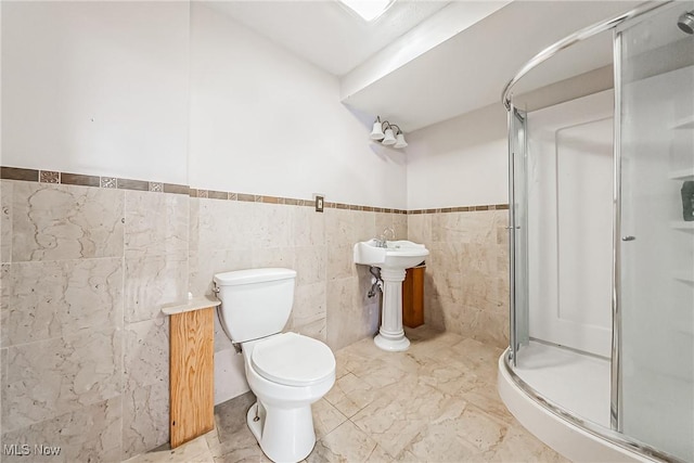 bathroom with toilet, tile walls, and a shower with shower door