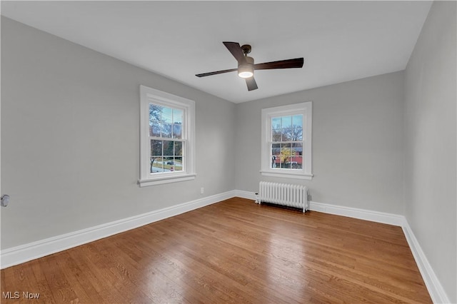 spare room featuring ceiling fan, wood-type flooring, and radiator