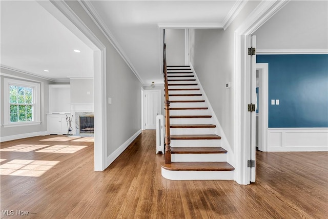 stairs with ornamental molding, a premium fireplace, and wood-type flooring