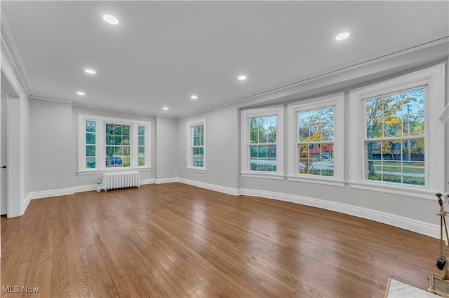 unfurnished room with crown molding, wood-type flooring, and radiator heating unit