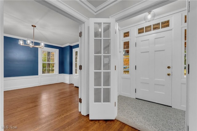 foyer entrance featuring ornamental molding, hardwood / wood-style floors, and a notable chandelier