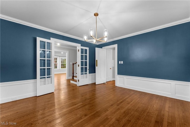 empty room featuring crown molding, dark wood-type flooring, french doors, and a chandelier