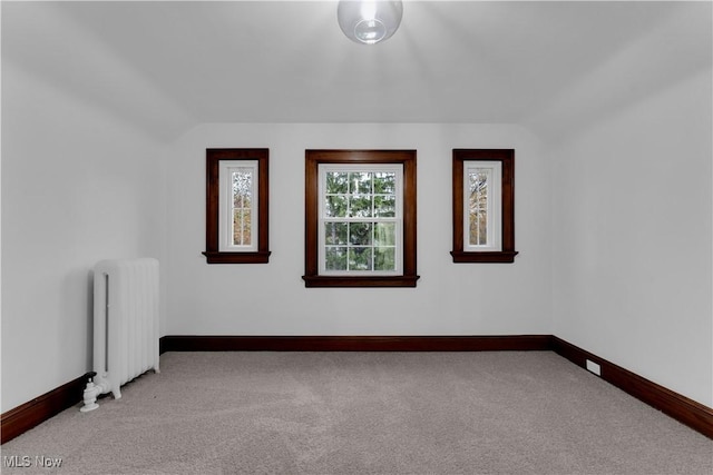 carpeted empty room with lofted ceiling and radiator