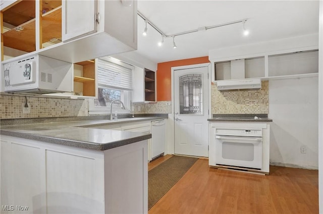 kitchen with white cabinetry, white appliances, wall chimney range hood, hardwood / wood-style floors, and backsplash