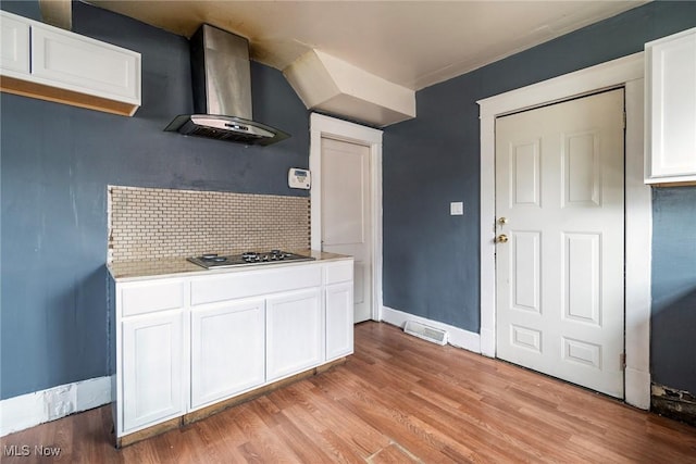 kitchen with white cabinetry, wall chimney exhaust hood, stainless steel gas stovetop, and backsplash