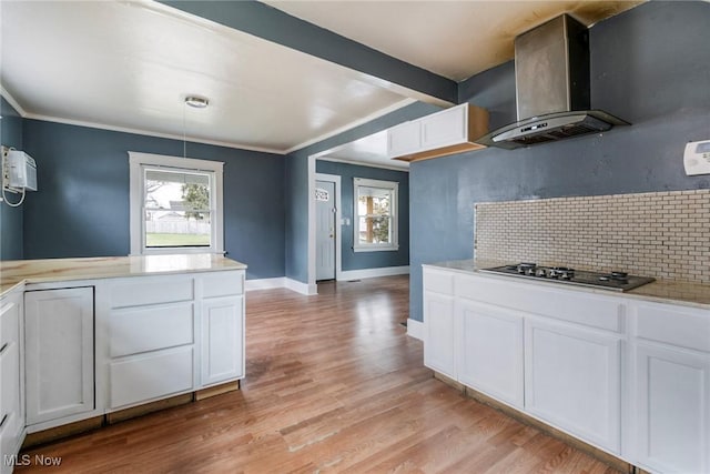 kitchen featuring white cabinets, backsplash, stainless steel gas cooktop, wall chimney exhaust hood, and light hardwood / wood-style flooring