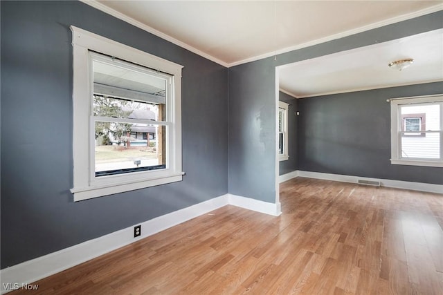 empty room with crown molding and light hardwood / wood-style flooring