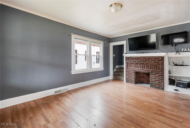 unfurnished living room with hardwood / wood-style flooring, a fireplace, and ornamental molding