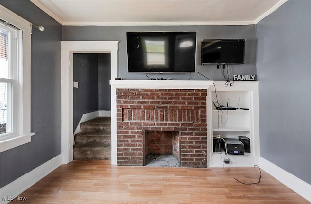 unfurnished living room with ornamental molding, hardwood / wood-style floors, and a brick fireplace