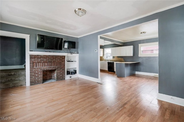 unfurnished living room featuring crown molding, a healthy amount of sunlight, a brick fireplace, and light wood-type flooring