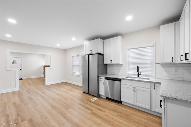 kitchen with white cabinetry, sink, light stone countertops, and appliances with stainless steel finishes