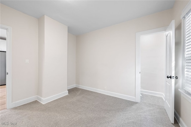 unfurnished bedroom featuring stainless steel refrigerator and light carpet