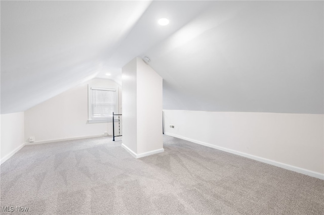 bonus room with lofted ceiling and light colored carpet