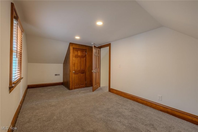 bonus room with lofted ceiling and light colored carpet