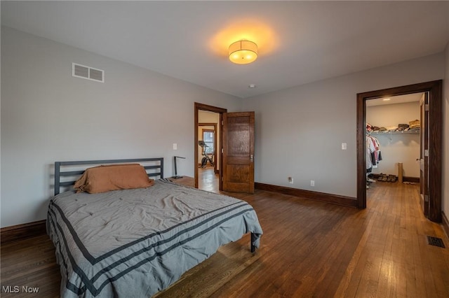 bedroom featuring a walk in closet, dark hardwood / wood-style flooring, and a closet