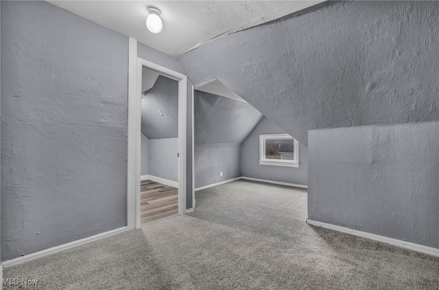 bonus room with lofted ceiling, carpet flooring, and a textured ceiling