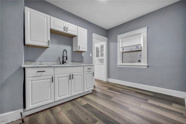 kitchen featuring white cabinetry, sink, light stone counters, and dark hardwood / wood-style floors