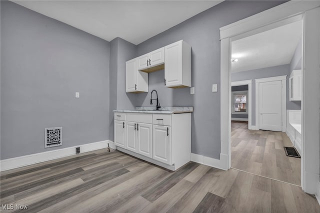 kitchen featuring sink, light hardwood / wood-style flooring, and white cabinets