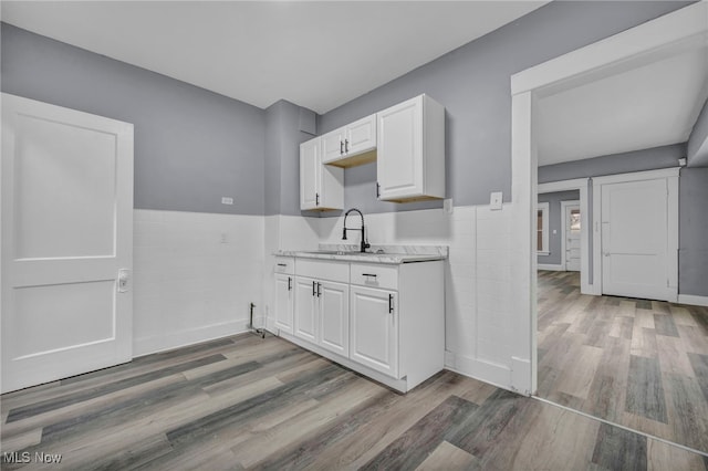 kitchen featuring tile walls, sink, white cabinets, and light wood-type flooring