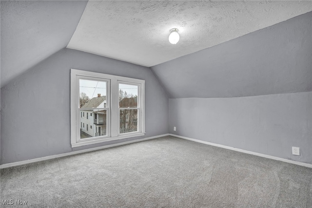 bonus room with vaulted ceiling, a textured ceiling, and carpet