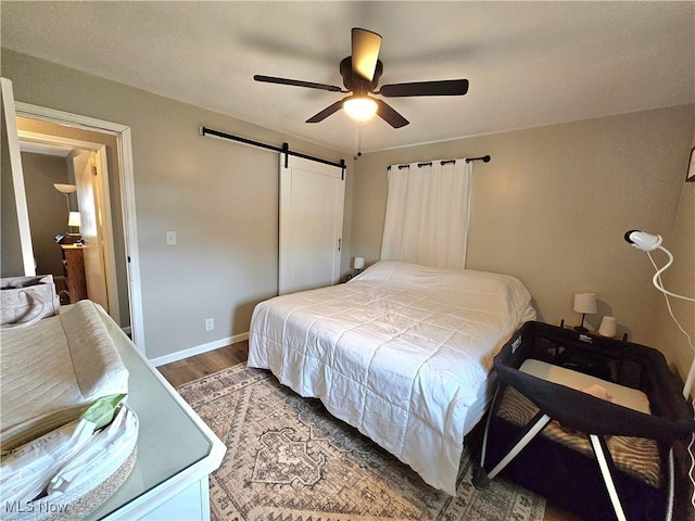 bedroom with wood-type flooring, a barn door, and ceiling fan