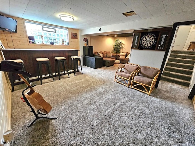 living room featuring carpet floors, wooden walls, and indoor bar