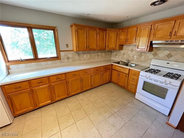 kitchen featuring sink, white gas stove, backsplash, and light tile patterned floors