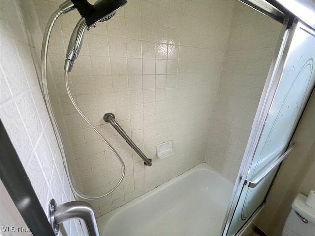 bathroom with toilet and tiled shower / bath