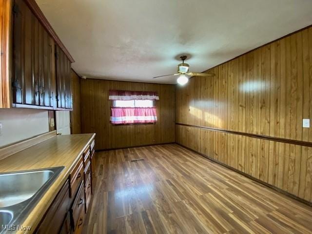 unfurnished dining area featuring dark hardwood / wood-style floors, ceiling fan, and wood walls