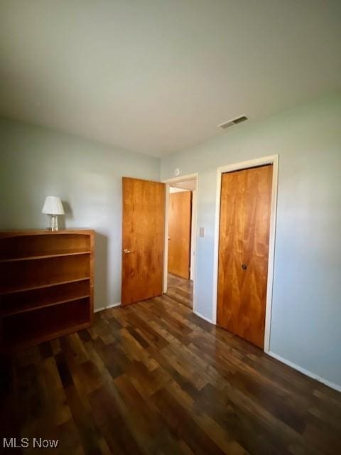 bedroom with dark wood-type flooring and a closet