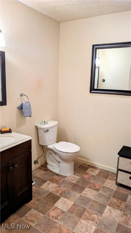 bathroom featuring vanity, toilet, and a textured ceiling