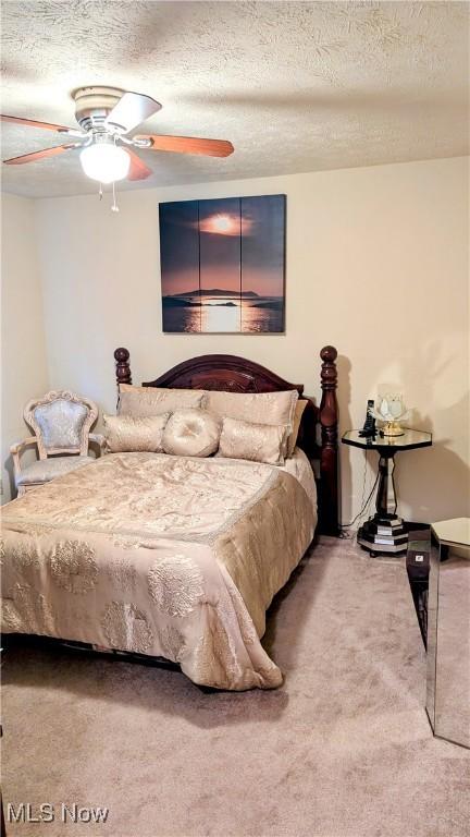 bedroom with ceiling fan, a textured ceiling, and carpet