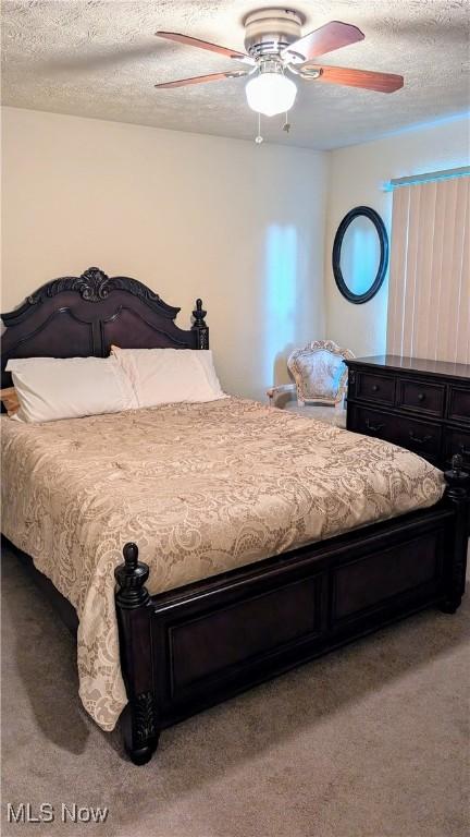 carpeted bedroom featuring ceiling fan and a textured ceiling