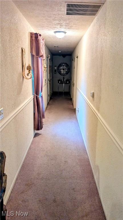 hallway featuring carpet flooring and a textured ceiling