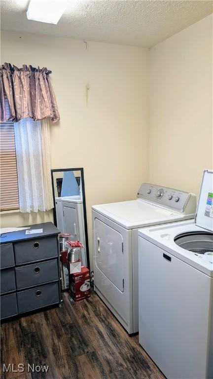 laundry room featuring washer and dryer, dark wood-type flooring, and a textured ceiling