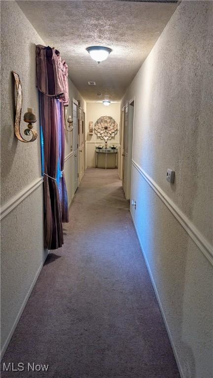 hallway featuring carpet floors and a textured ceiling