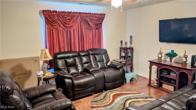 living room featuring ceiling fan, hardwood / wood-style floors, and a textured ceiling