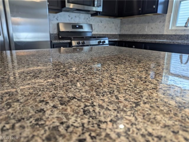 kitchen with dark stone countertops, backsplash, and appliances with stainless steel finishes