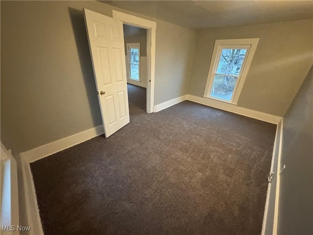 empty room featuring a healthy amount of sunlight and dark carpet