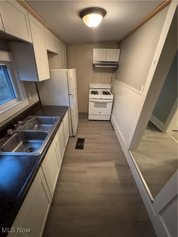 kitchen with sink, white appliances, white cabinets, and light wood-type flooring