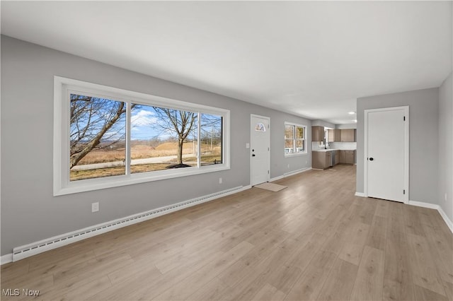 unfurnished living room featuring a baseboard radiator and light hardwood / wood-style floors