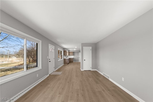 unfurnished living room with a baseboard radiator and light hardwood / wood-style flooring